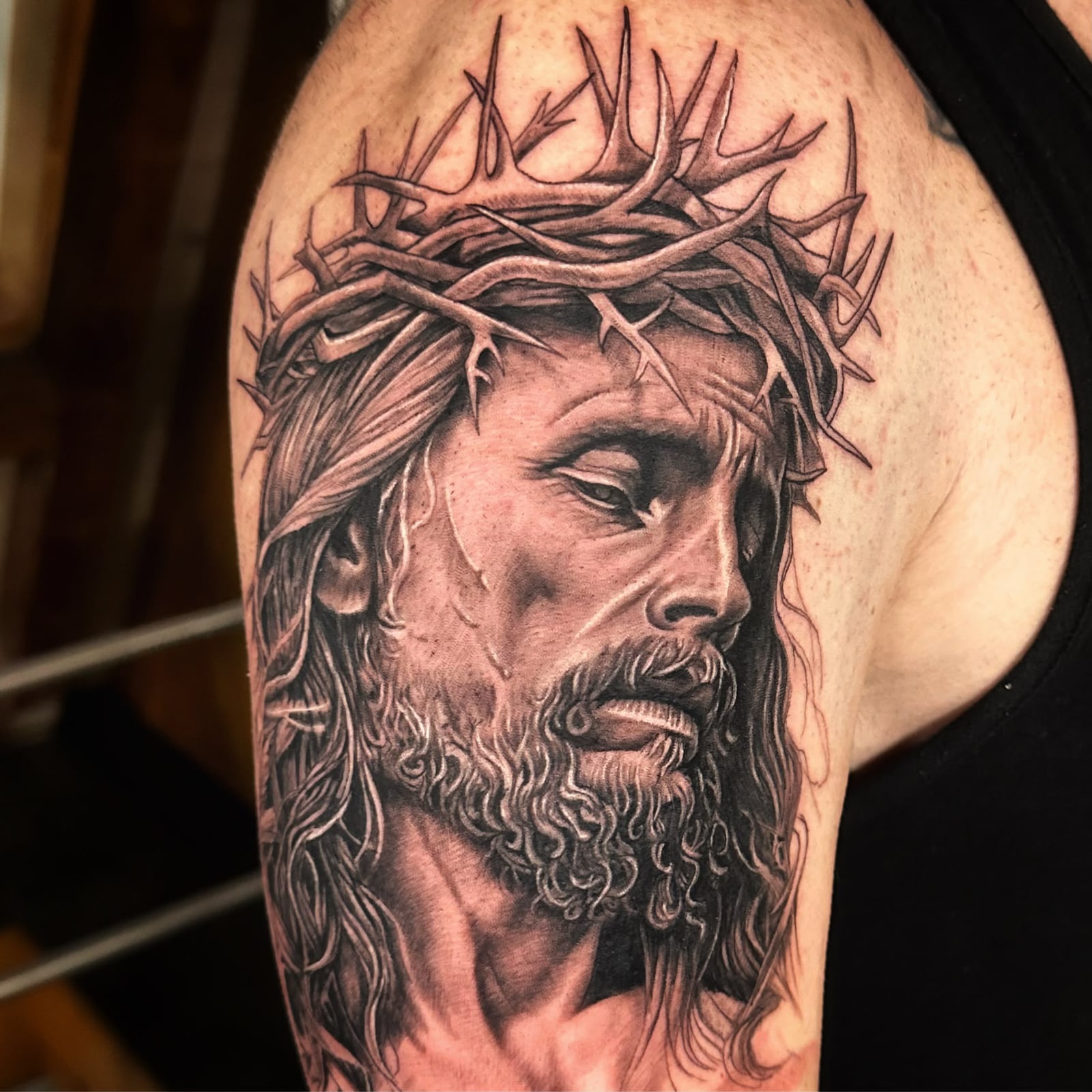 Tattoo: Jesus-Porträt mit Dornenkrone am Oberarm