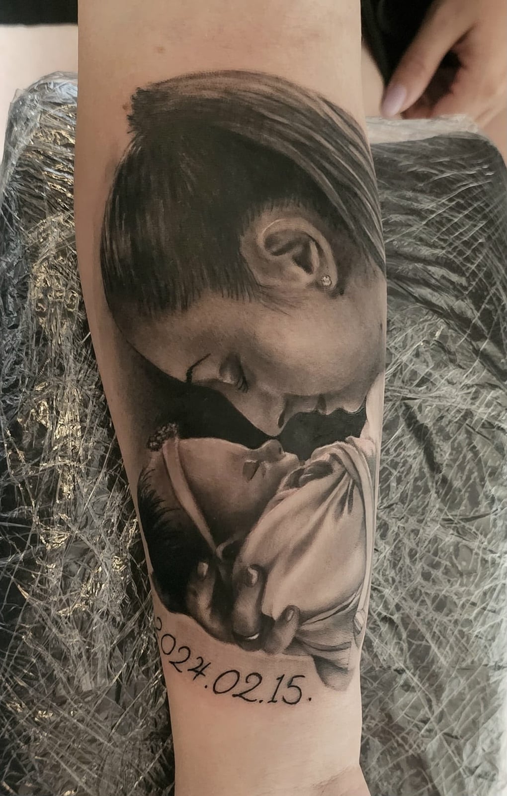 Tattoo: Mutter-Kind-Porträt mit Datum am Unterarm