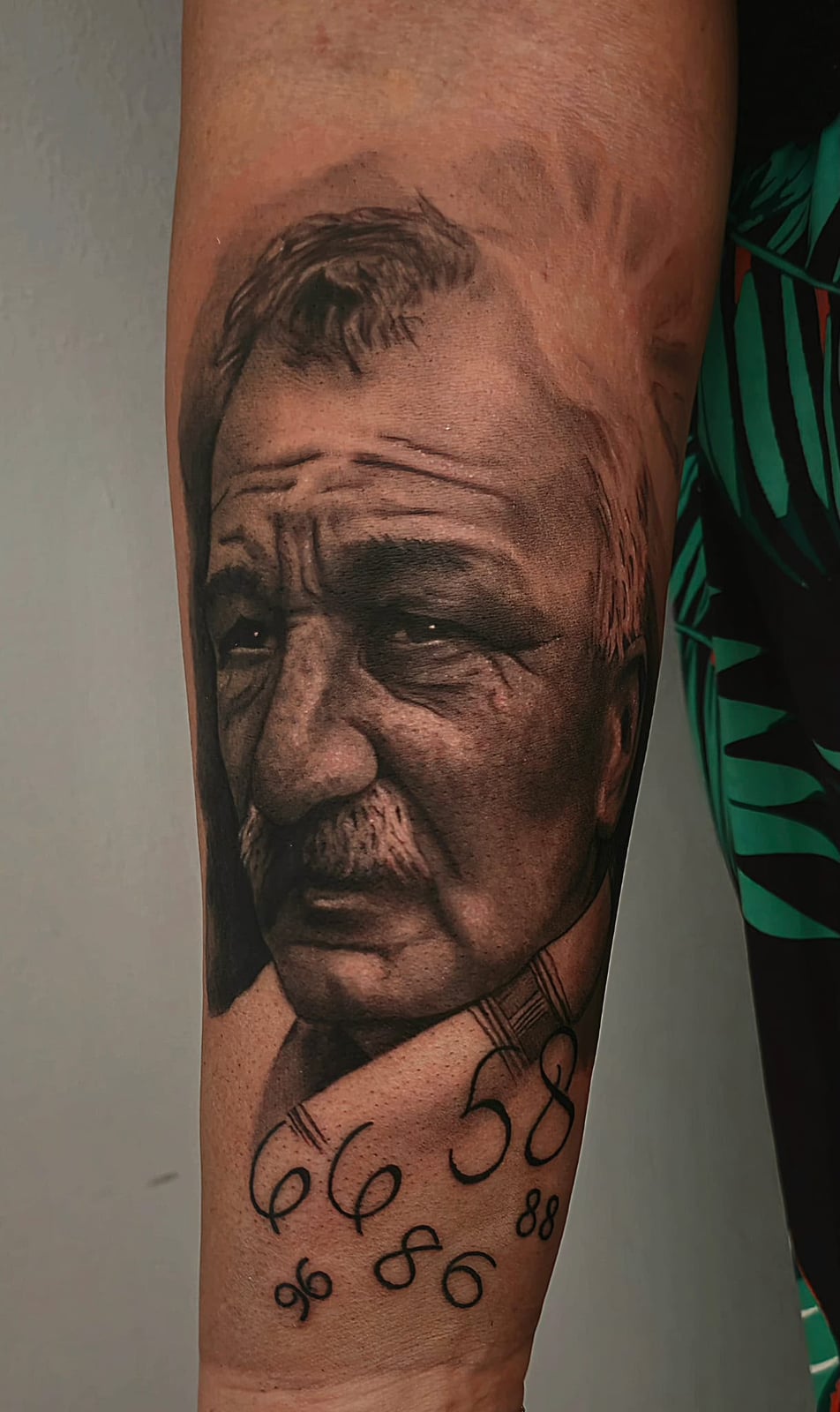 Tattoo: Porträt eines älteren Mannes mit Zahlen am Unterarm