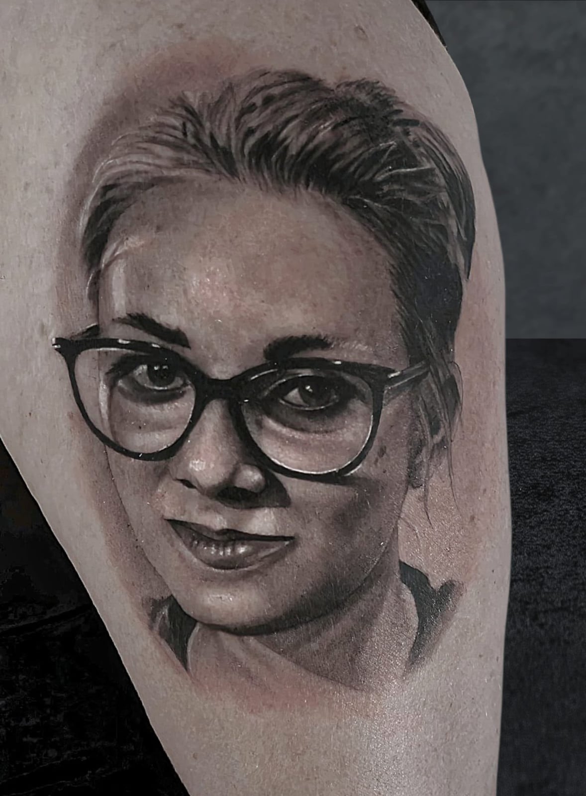 Tattoo: Frauenporträt mit Brille am Oberarm