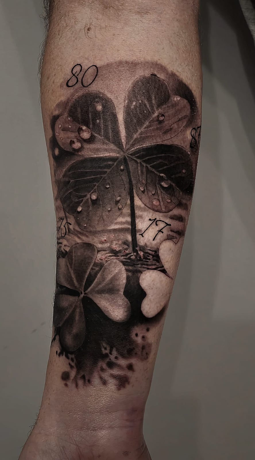 Tattoo: Kleeblatt mit Wassertropfen und Zahlen am Unterarm