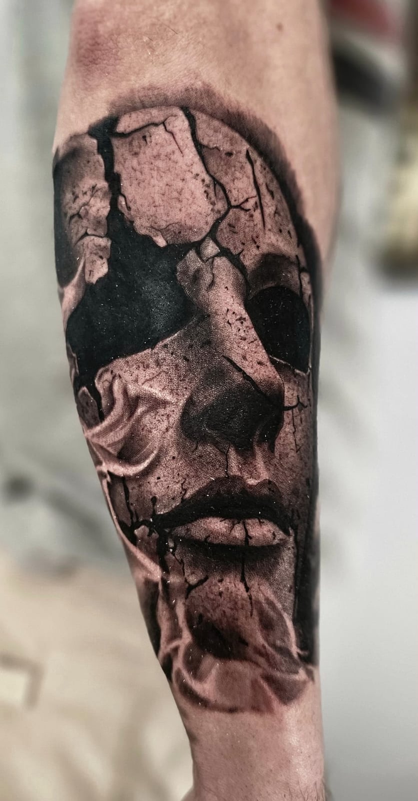 Tattoo: gesprungene Gesichtsmaske am Unterschenkel