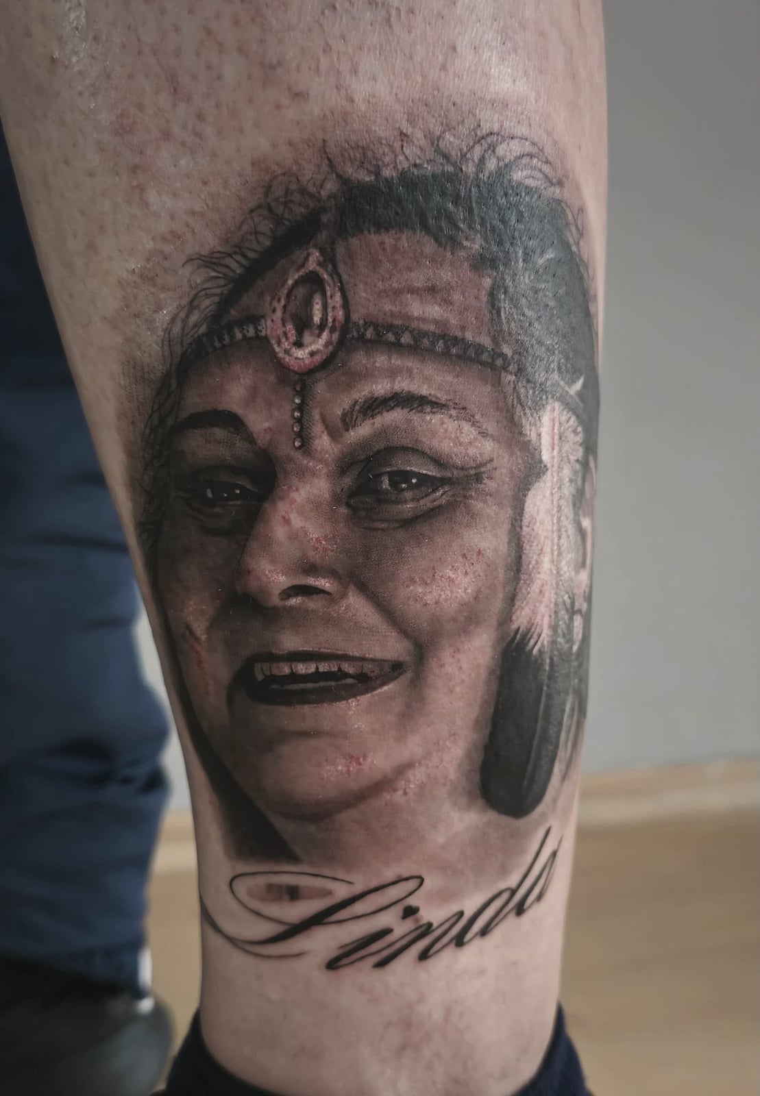 Tattoo: Frauenporträt mit Schriftzug am Unterschenkel