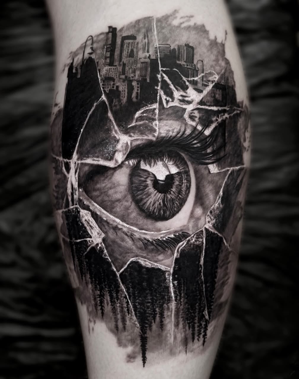Tattoo: Auge mit Stadtsilhouette in Glasbruch am Unterschenkel