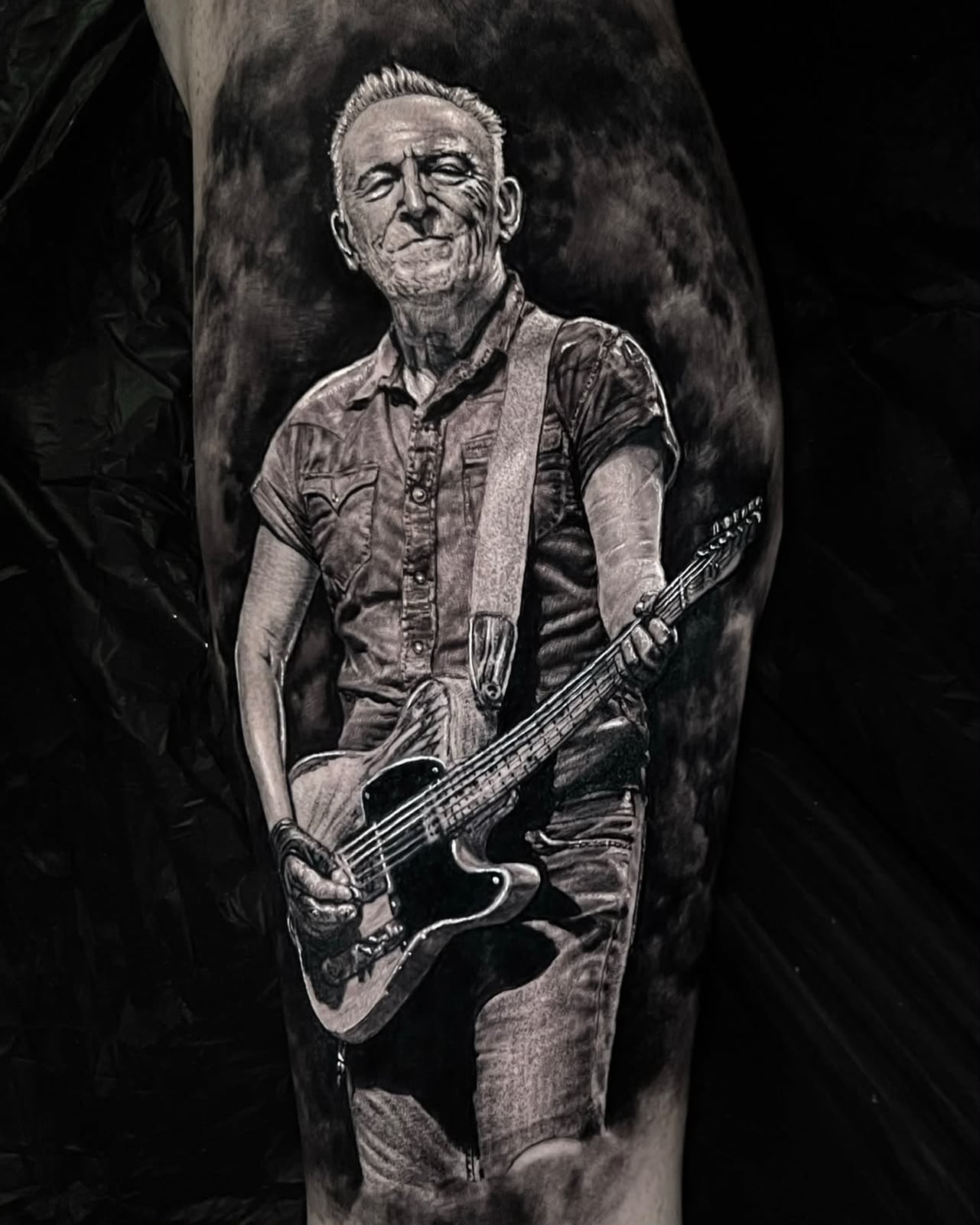 Tattoo: Musiker mit Gitarre am Unterschenkel