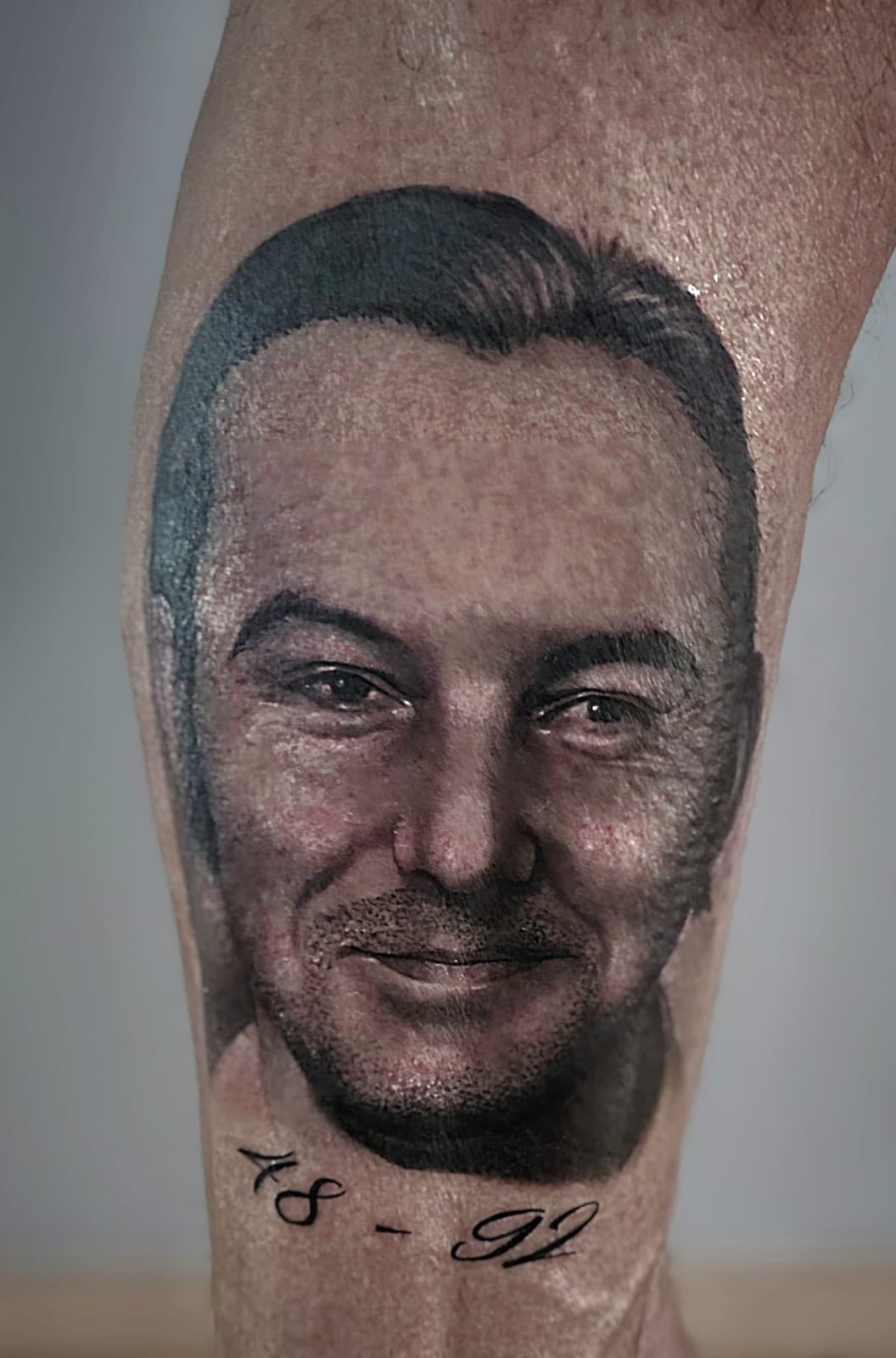 Tattoo: Männerporträt mit Datum am Unterschenkel